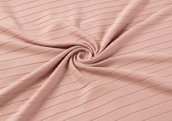 A close-up of light pink bandage fabric with subtle horizontal stripes and a slight shimmer